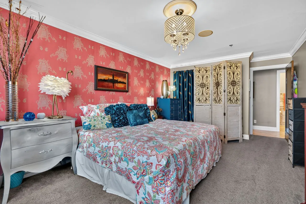 Bedroom featuring patterned wallpaper, crown molding, and a crystal chandelier