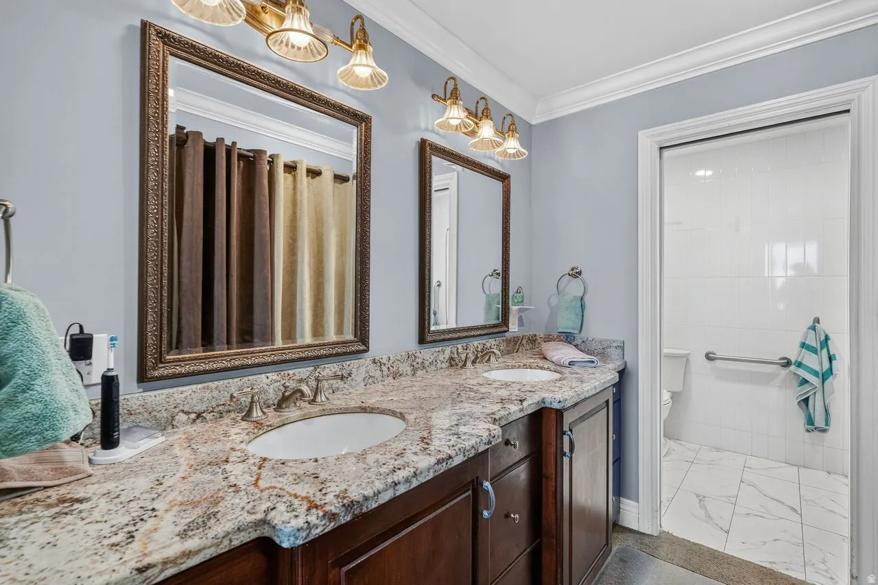 Double vanity with stone countertop, undermount sinks, and dark wood cabinetry