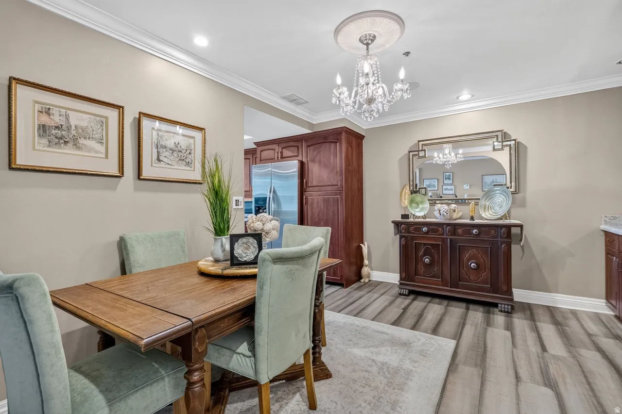 Elegant formal dining room showcasing a wood-top table with turned legs, upholstered dining chairs in soft sage, and a crystal chandelier overhead