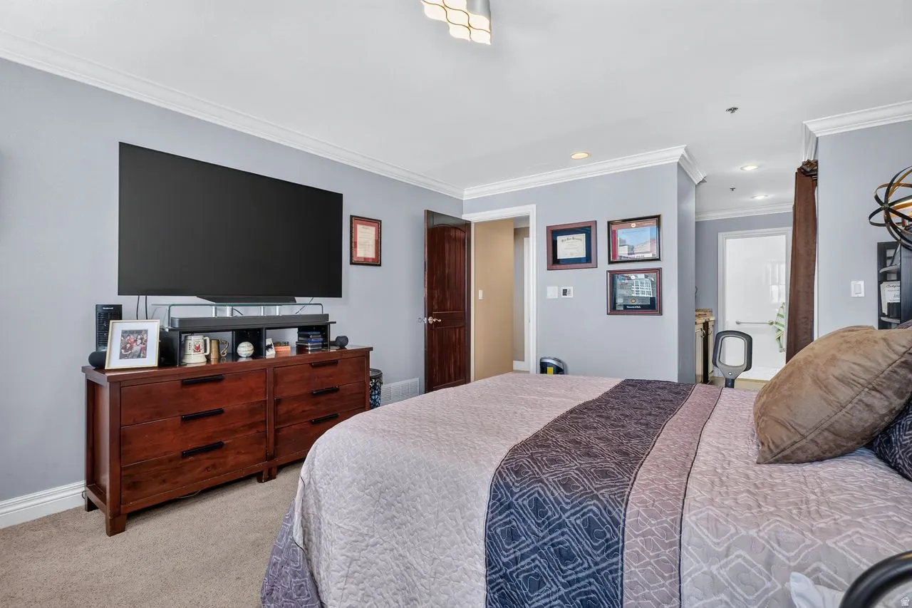 Bedroom featuring grey walls, crown molding, and carpeted flooring