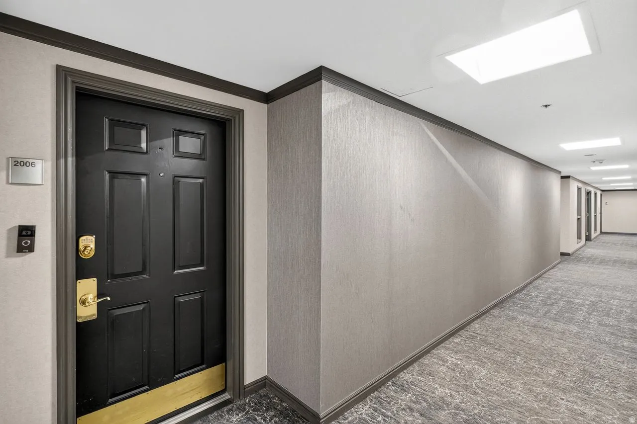 Modern corridor featuring polished concrete flooring with geometric patterning, neutral textured wall finishes, and recessed ceiling lighting