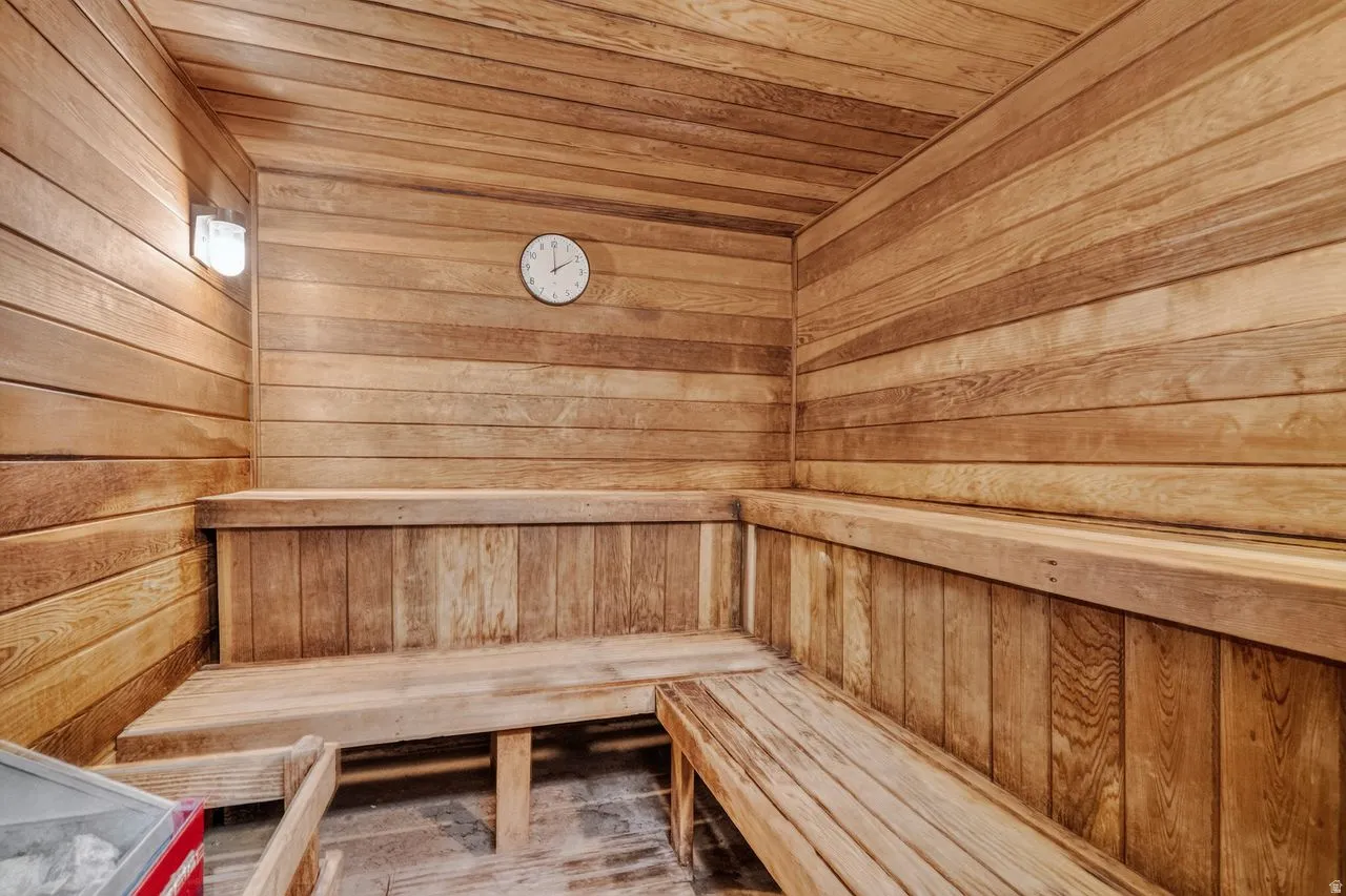 Custom sauna featuring horizontal wood-panel walls, built-in multi-level wood benches, and a wall-mounted light fixture