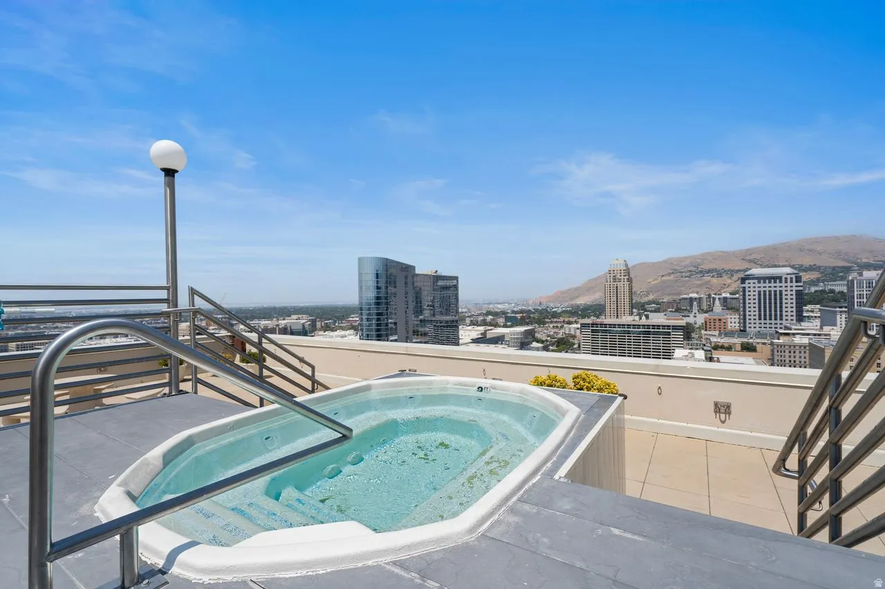 Rooftop spa with illuminated soaking tub overlooking downtown skyline and surrounding mountain landscape