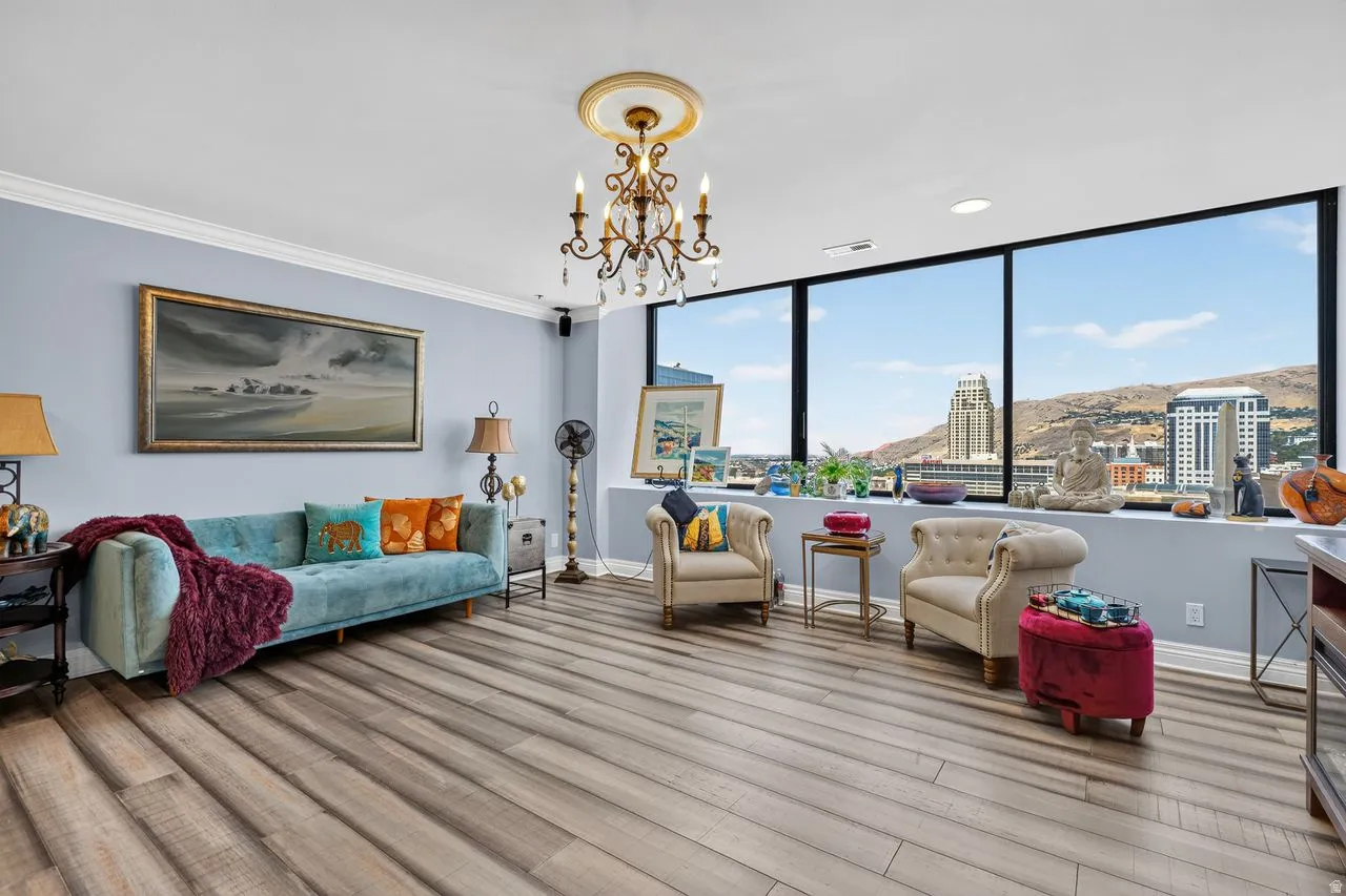 Living area featuring expansive windows, wood-finish flooring, and crown molding