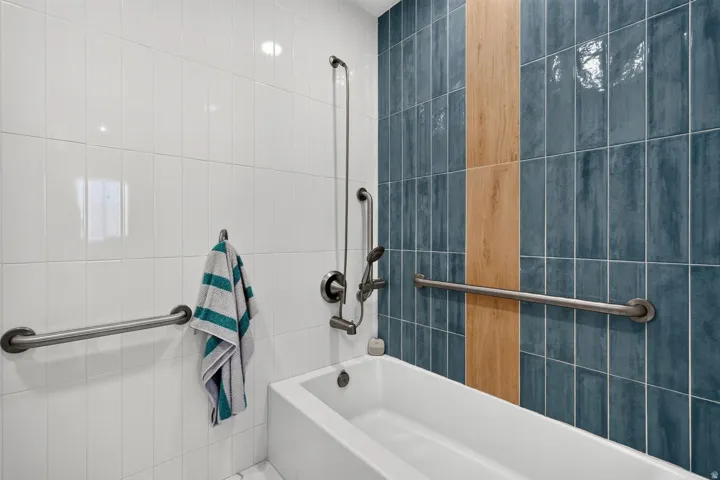 Soaking tub with white subway tile and blue vertical tile accents