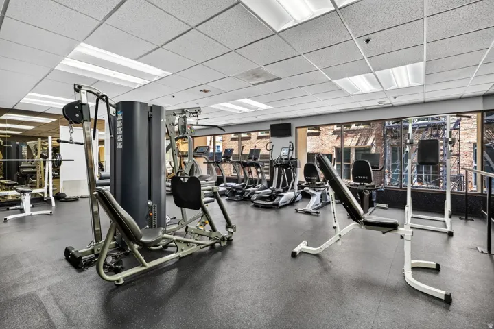 Fitness center featuring rubber flooring, abundant natural light through extensive windows, and a variety of exercise equipment including strength training machines and cardio machines