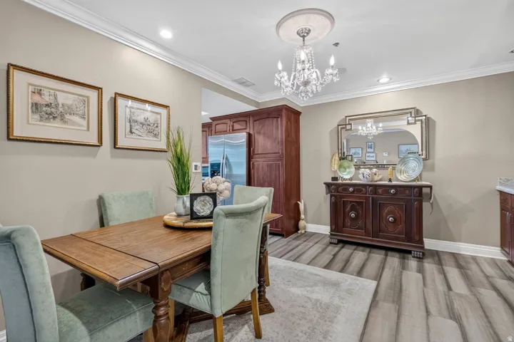 Elegant formal dining room showcasing a wood-top table with turned legs, upholstered dining chairs in soft sage, and a crystal chandelier overhead