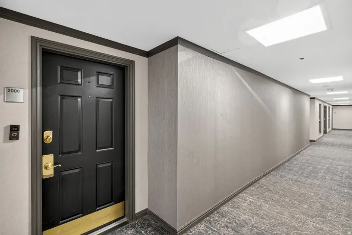 Modern corridor featuring polished concrete flooring with geometric patterning, neutral textured wall finishes, and recessed ceiling lighting