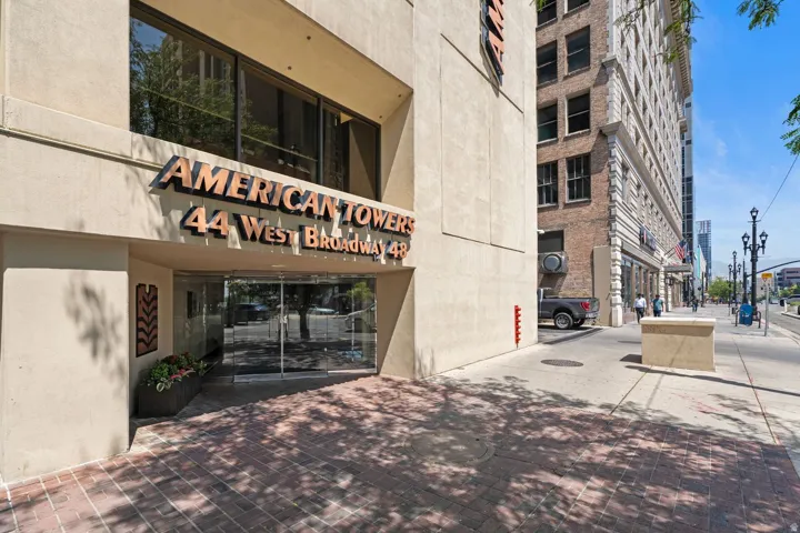 Prominent building entrance with "AMERICAN TOWERS 44 West Broadway 4R" signage, framed by a patterned brick walkway