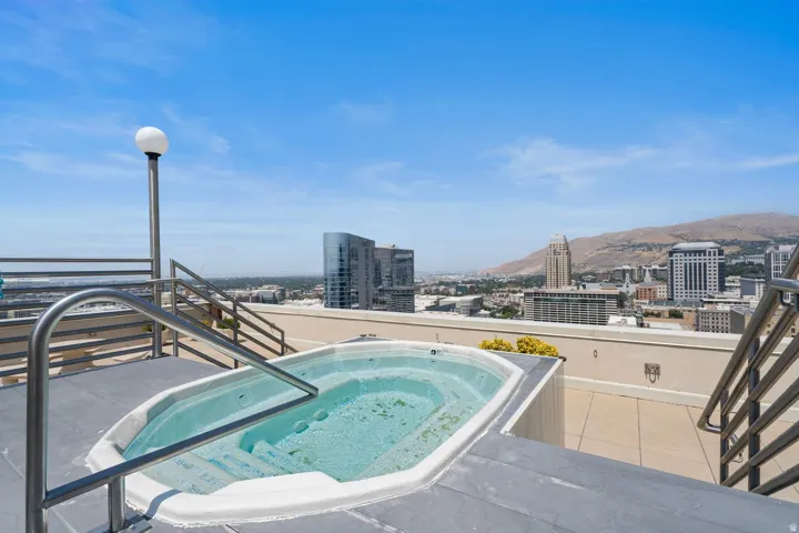 Rooftop spa with illuminated soaking tub overlooking downtown skyline and surrounding mountain landscape