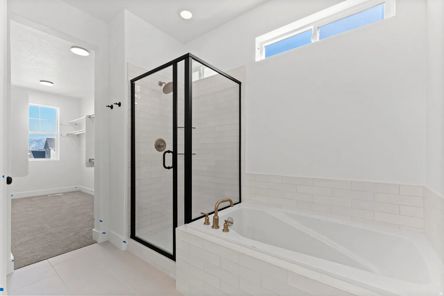Spacious bathroom featuring a built-in tub, separate glass-enclosed shower with subway tile, and a transom window