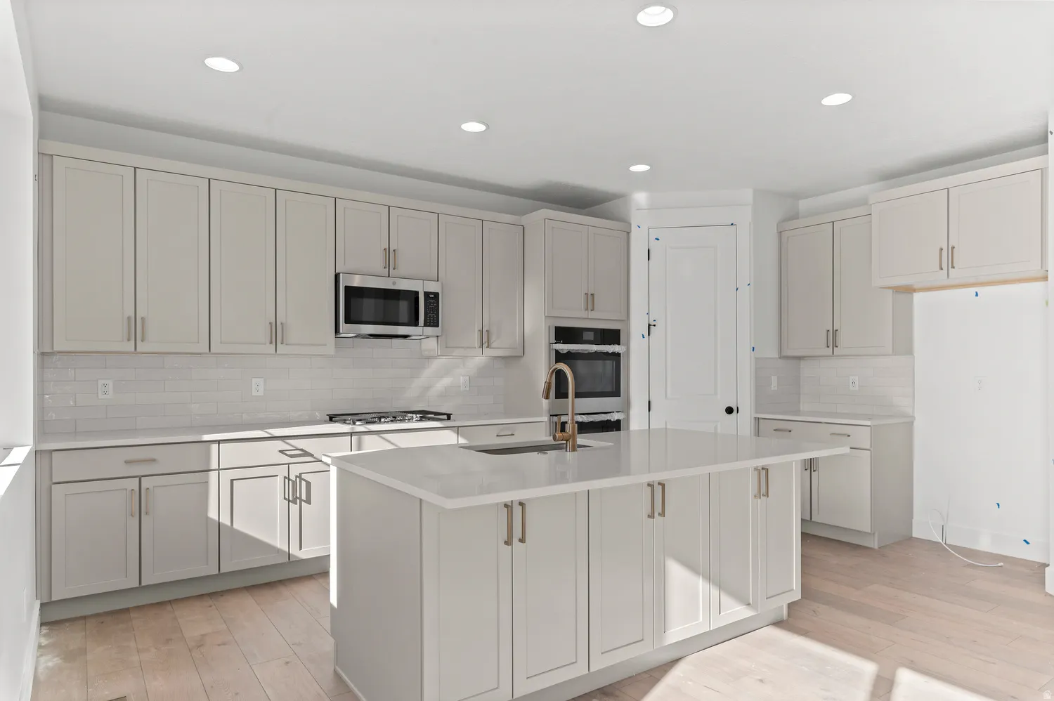 Kitchen featuring a central island, recessed lighting, light-toned cabinetry, light wood-finish flooring, and subway tile backsplash