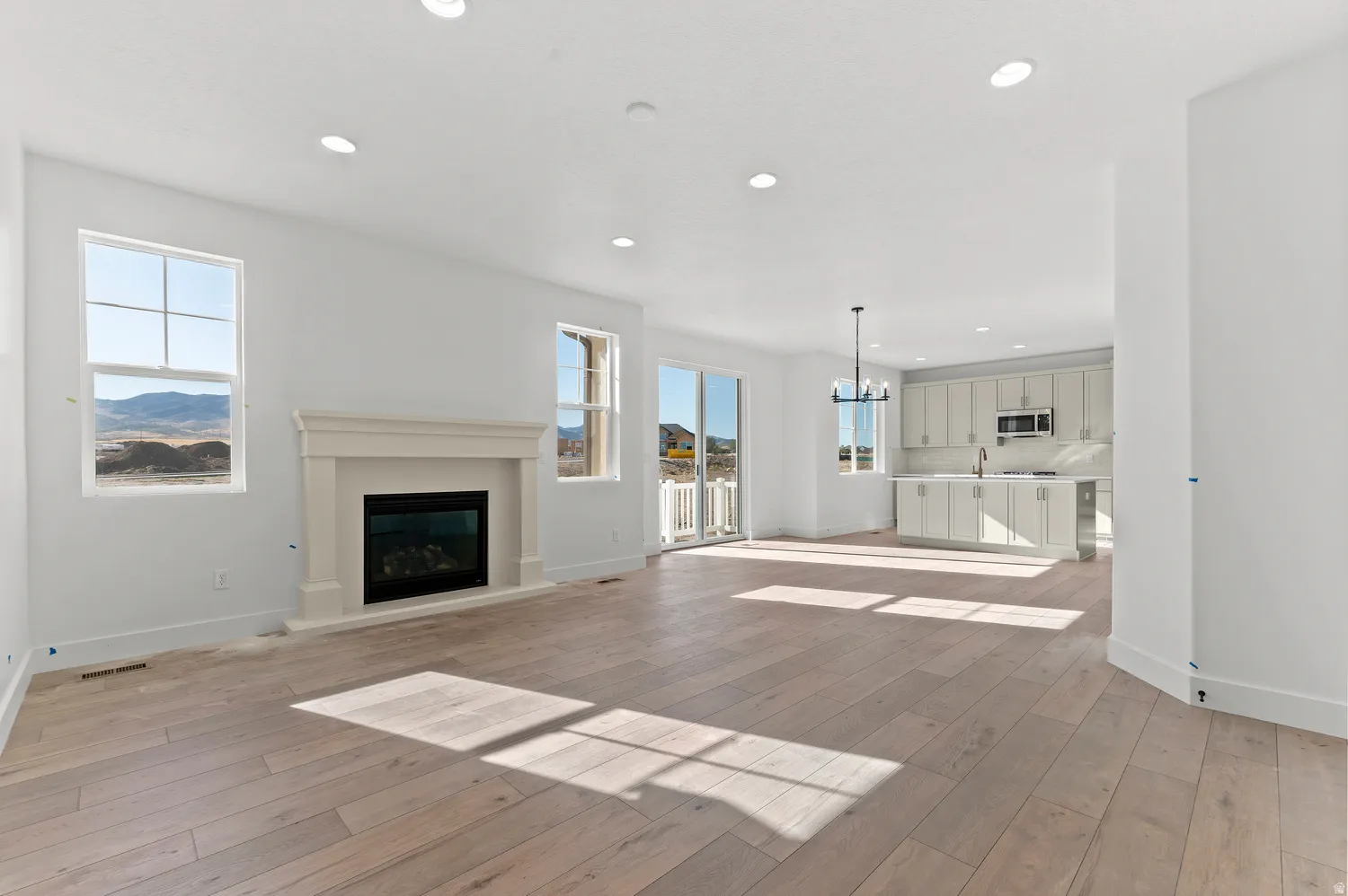 Wood-finish flooring throughout, recessed lighting, and a prominent fireplace with a substantial mantel