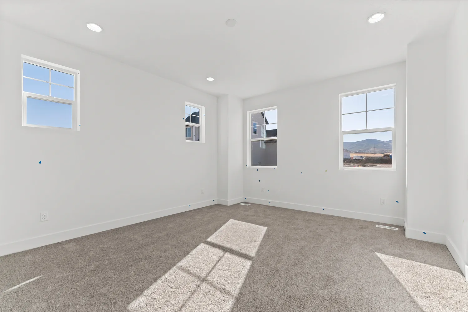 Neutral tone wall paint, recessed ceiling lighting, light gray carpeting, multiple windows, and white trim