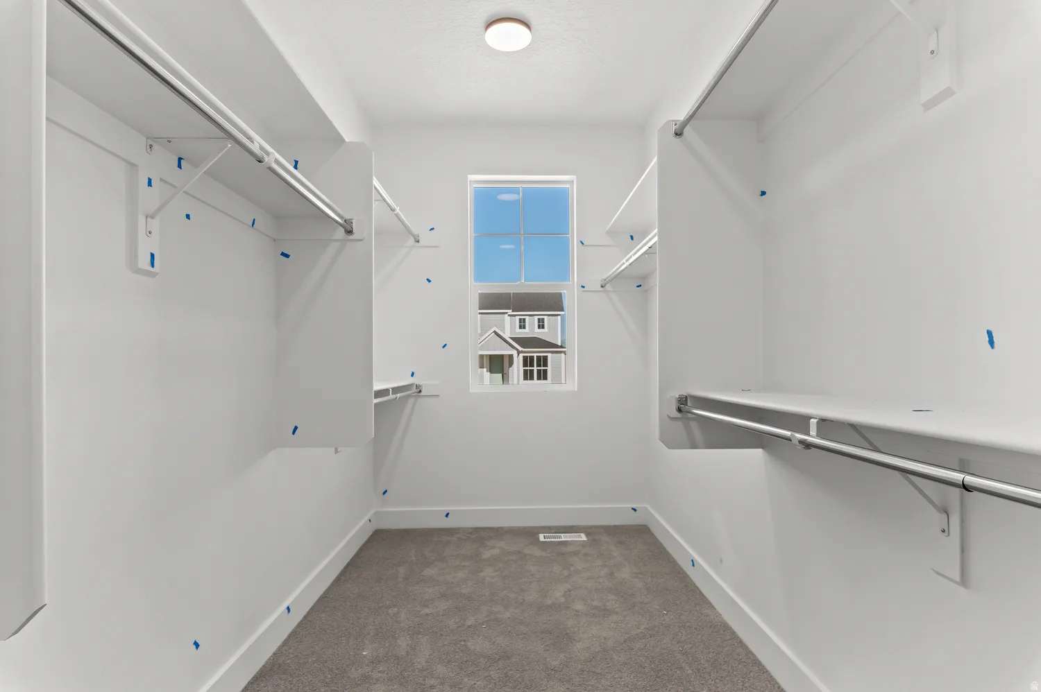 Carpeted walk-in closet with built-in shelving and hanging rods