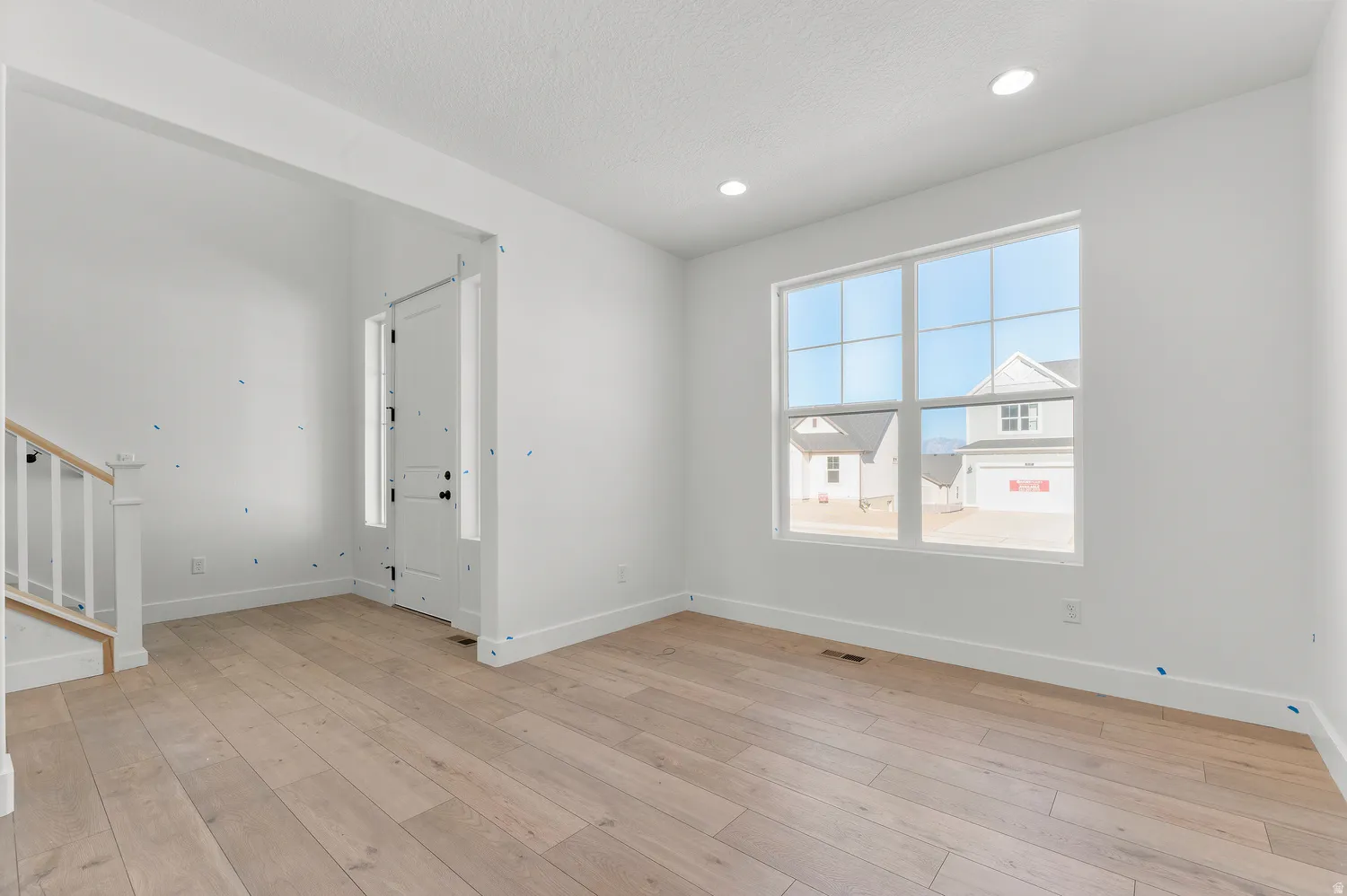 Recessed lighting, wood-finish flooring, white trim, and a multi-pane window