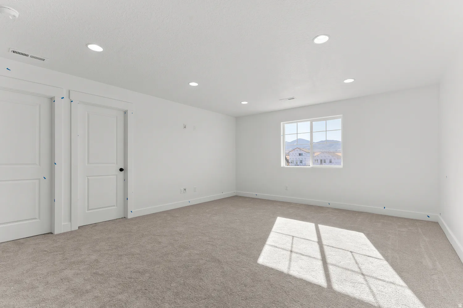 Recessed lighting, neutral carpeting, white interior doors, and a window with mountain scenery