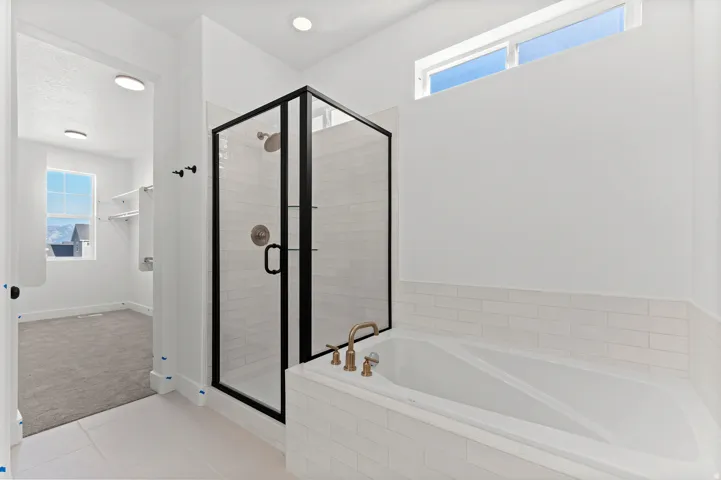 Spacious bathroom featuring a built-in tub, separate glass-enclosed shower with subway tile, and a transom window