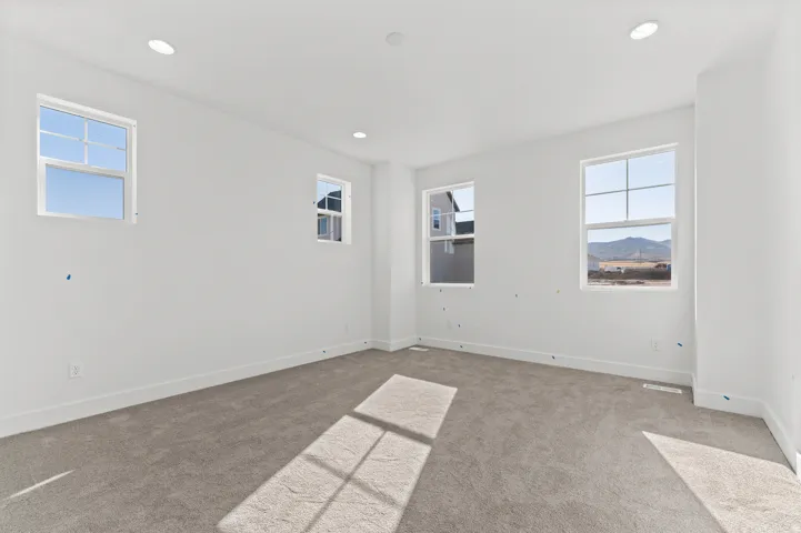 Neutral tone wall paint, recessed ceiling lighting, light gray carpeting, multiple windows, and white trim