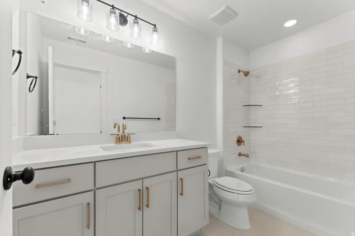 White subway tile shower surround with dual recessed shelves, a built-in tub, and bronze fixtures