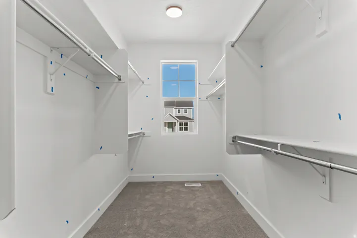 Carpeted walk-in closet with built-in shelving and hanging rods