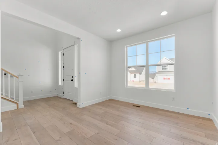 Recessed lighting, wood-finish flooring, white trim, and a multi-pane window