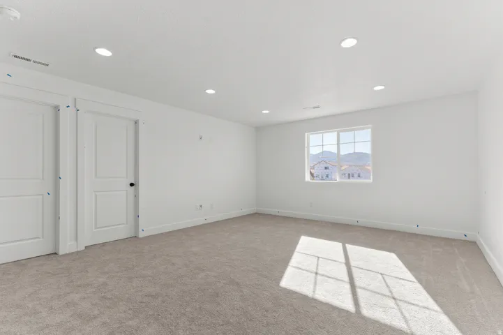 Recessed lighting, neutral carpeting, white interior doors, and a window with mountain scenery