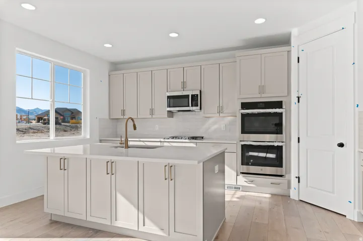 Light-filled kitchen with a central island, recessed lighting, double wall ovens, a built-in microwave, and wood-finish flooring