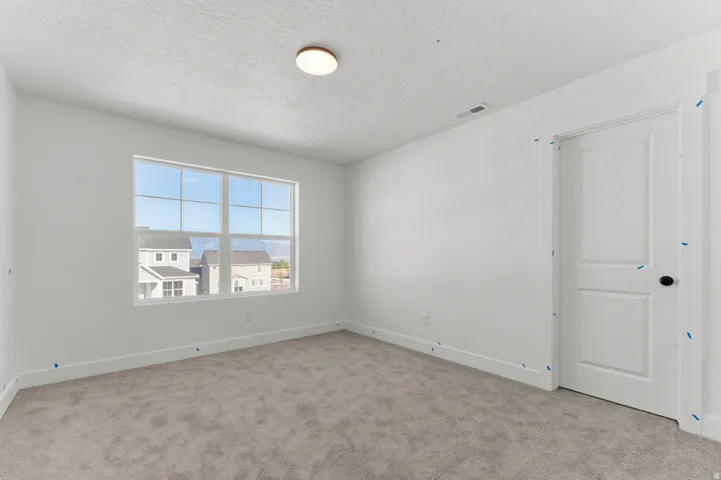 Neutral tone wall paint, carpet flooring, a multi-pane window, and a flush-mount ceiling light