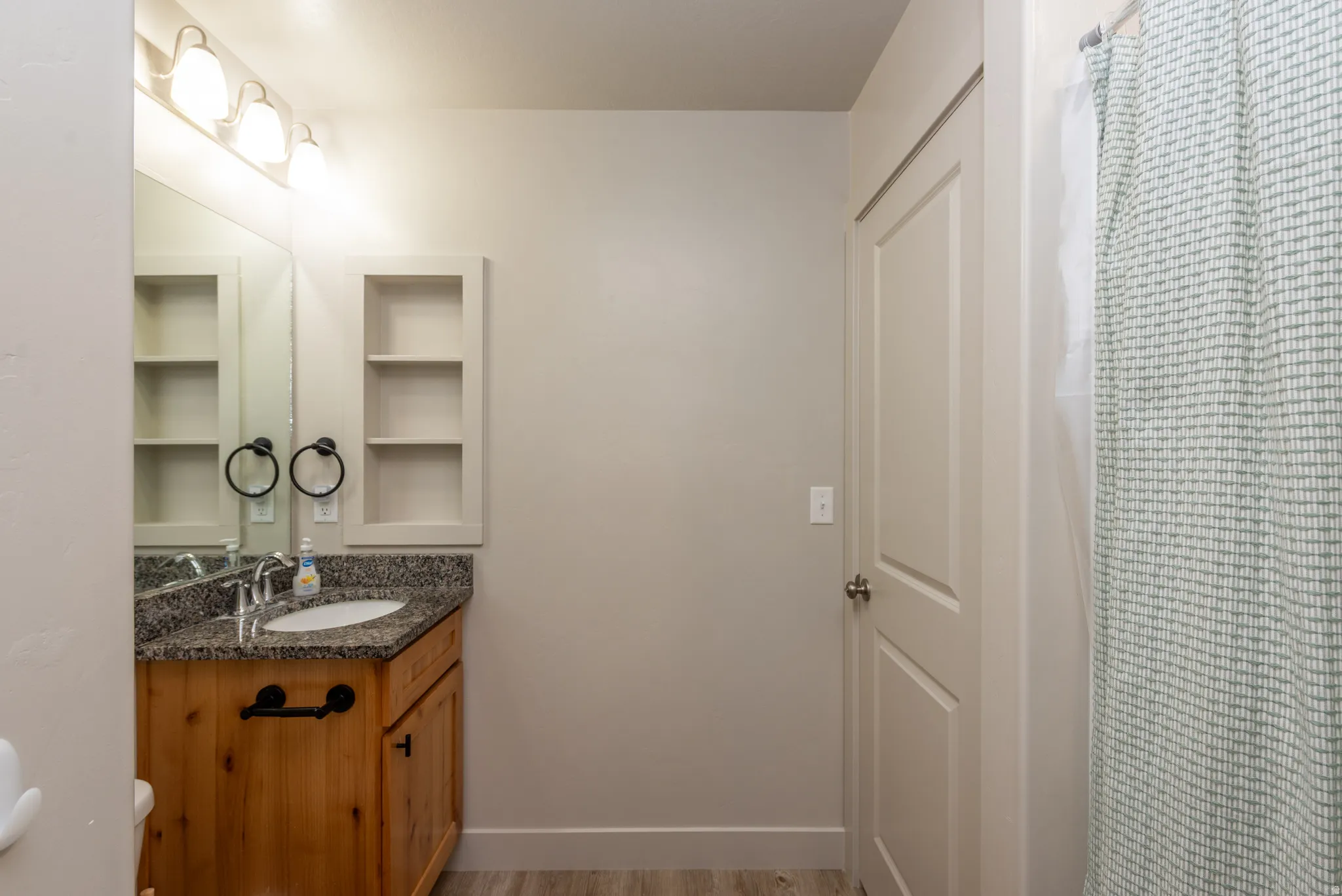 Bathroom vanity featuring a granite-style countertop, undermount sink, and wood-finish cabinetry