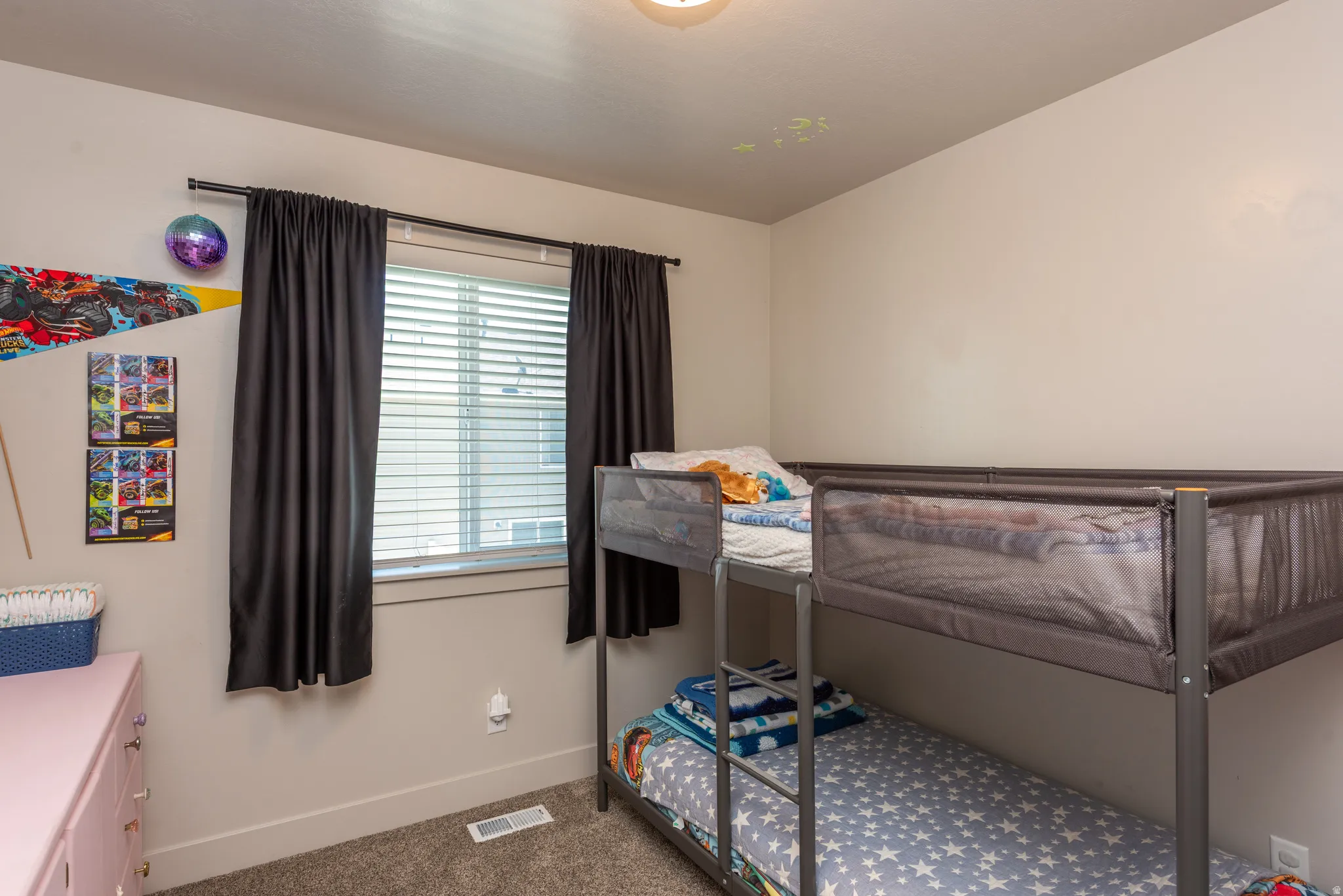 Neutral tone walls featuring a window with horizontal blinds and dark curtains, carpeted flooring, and a flush mount ceiling light fixture