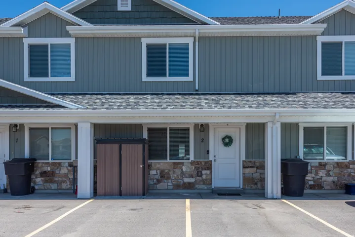 Multi-unit exterior featuring vertical siding, stone accents, white trim, and a gray shingle roof