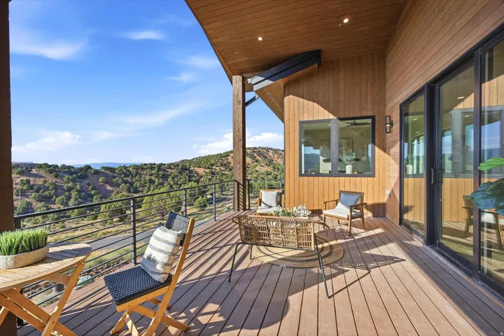 Expansive covered deck featuring wood-finish decking, black metal railings, and a wood-paneled exterior