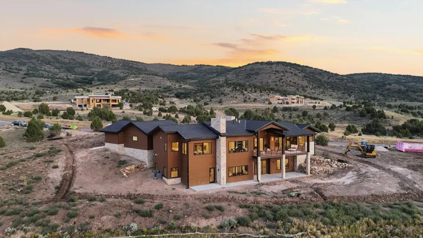 Modern architectural residence featuring warm-toned exterior cladding with expansive glazing, pitched roof lines, and mixed material finishes