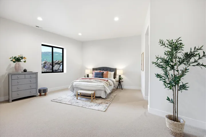 Bright bedroom featuring neutral-toned carpeting and recessed lighting
