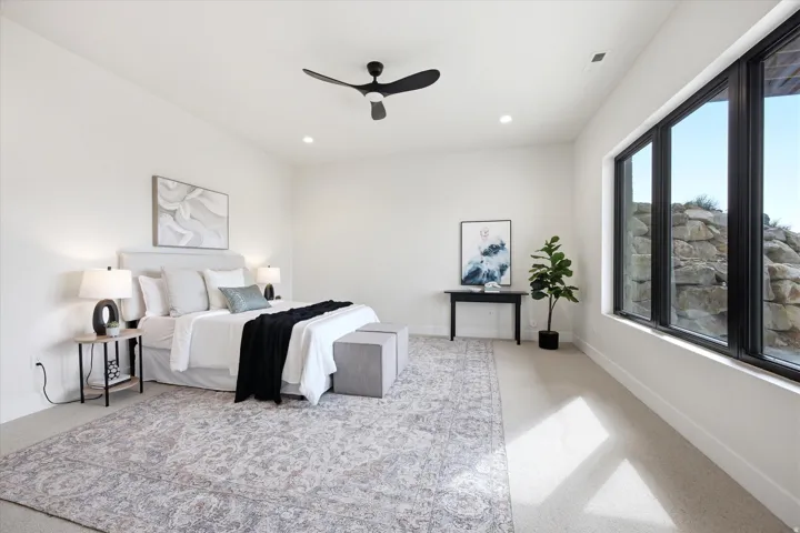 Bright bedroom featuring a black ceiling fan, recessed lighting, and large black-framed windows