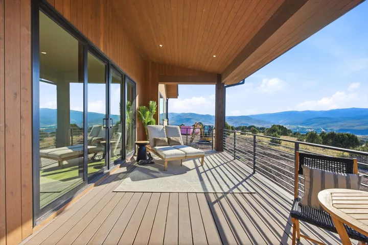 Expansive covered deck featuring wood-look flooring, wood-paneled ceiling, and a cable railing system