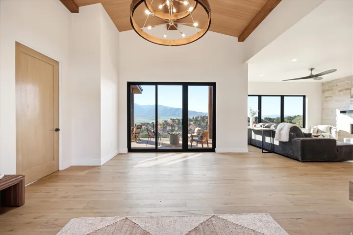 Spacious entryway featuring a vaulted ceiling with exposed wood beams and a contemporary chandelier
