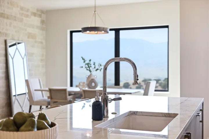 Kitchen island featuring an undermount sink, gooseneck faucet, and light-toned countertop