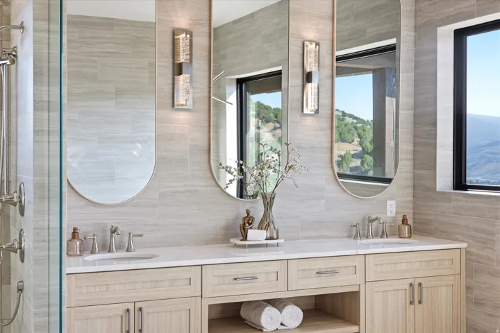 Dual vanity featuring light wood-finish cabinetry, white countertops, and undermount sinks with brushed nickel fixtures
