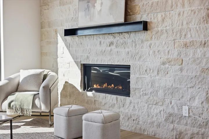 Stone-clad fireplace with an integrated linear firebox and a black floating mantle
