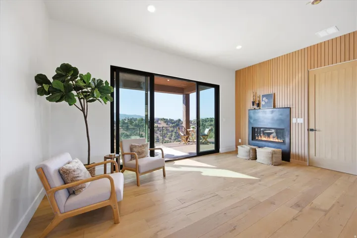 Spacious room featuring wood-finish flooring, a modern fireplace with a dark surround, and a wood-slat accent wall