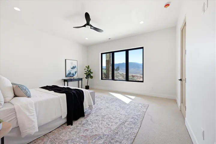 Recessed lighting, black framed window, modern ceiling fan, light-toned carpeting, and a light wood-finish door with black hardware
