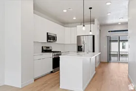Modern kitchen featuring white cabinetry, stainless steel appliances, a white subway tile backsplash, and light wood-finish flooring