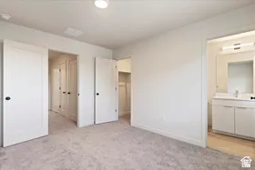 Neutral color palette throughout featuring recessed lighting, a built-in closet with shelving, a bathroom vanity with integrated sink, and wood-finish flooring