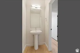 Pedestal sink with chrome faucet, framed mirror, and overhead lighting fixture