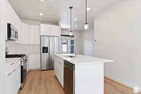Contemporary kitchen featuring a white subway tile backsplash, stainless steel appliances, and a central island with an integrated sink