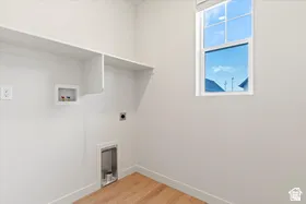 Dedicated laundry space featuring built-in shelving, wood-finish flooring, and a double-paned window