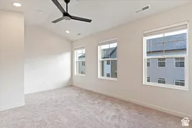 Spacious room featuring vaulted ceilings, recessed lighting, a modern ceiling fan, three double-hung windows, and plush carpet flooring