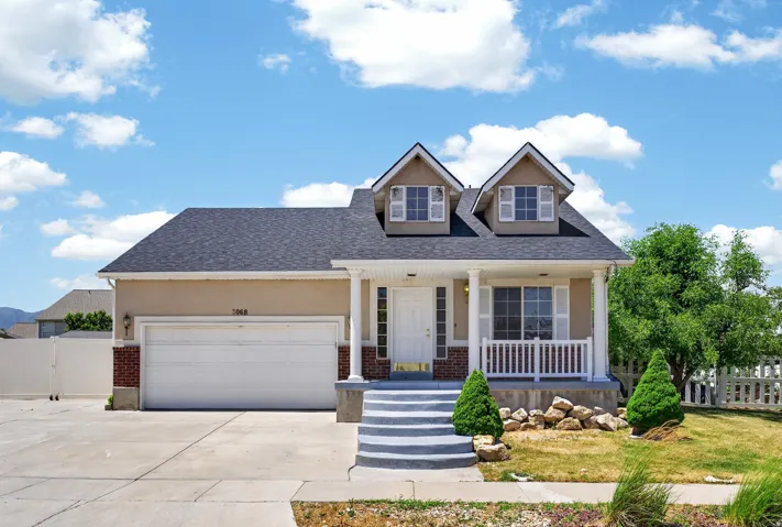 Classic two-story home featuring a welcoming front facade with dual dormers, white trim detailing, and a covered front porch